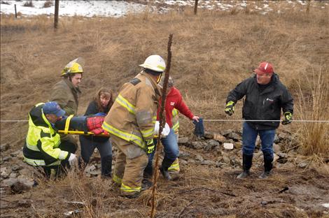 Emergency workers hold onto a cable to keep from slipping down a muddy ravine while carrying Stacie Rongwycsik-Lester to an ambulance. 