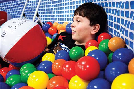 Isaac McNair sinks into the ball pit at the Winter Carnival at Polson High School.