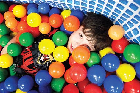 Isaac McNair sinks into the ball pit at the Winter Carnival at Polson High School.