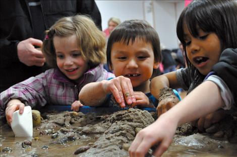 Tony Lozeau Black plays in squishy mud at a Science Night Exhibit. 