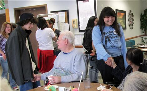 Upward Bound student Dez Kitsson, left, visits with a resident at St. Luke’s Extended Care facility.