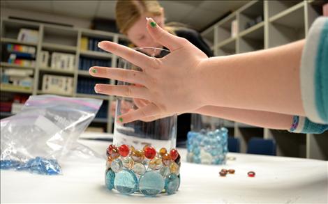 Translucent glass stones and sticky glue transform simple cylinders into candleholders, with the help of artistic hands.