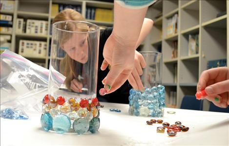 Translucent glass stones and sticky glue transform simple cylinders into candleholders, with the help of artistic hands.