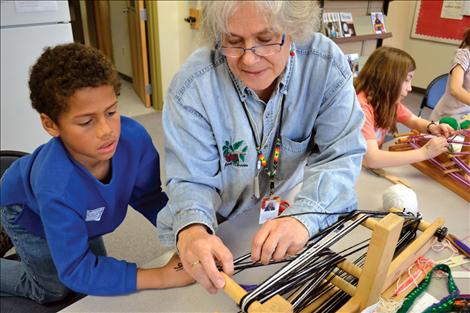 Artist Mary Sale helps a student with his inkle weaving.