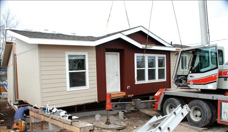 A crane drops half of Lucky and Barbara Donegan’s house into place in Polson.