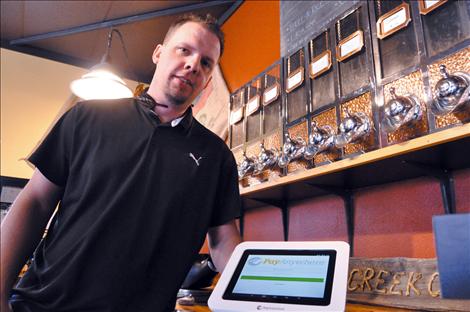 Justin Taylor installs a card swipe terminal at Dobson Creek Cofee shop in Ronan. 