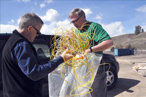 Lake County Solid Waste Manager Mark Nelson and Lake County Emergency Operations Director Steve Stanley place blasting caps into a garbage bag so proper disposal measures can be taken.