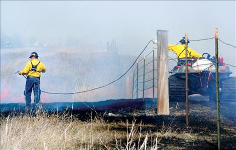 Firefighters negotiate a fenceline during a prescribed burn south of Ronan.