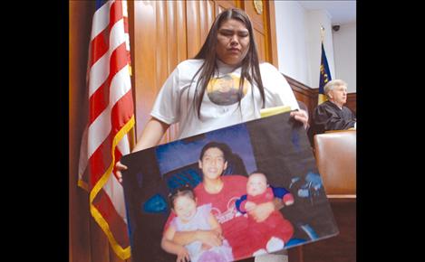 Kayla Ridgley leaves the witness stand with a photo of her cousin Laurence Kenmille and two of his children.  