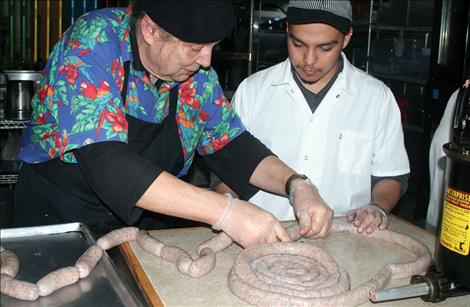 Bill Stoianoff shows Joseph Martinez how to roll the ends on sausage links. 