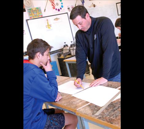 PHS art teacher Matt Holmes explains perspective to student Thunder Morales in art class.