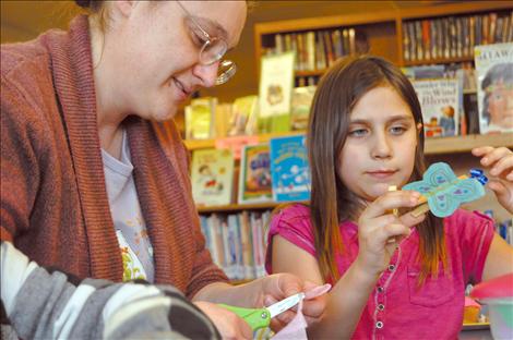 Emma Hoppe creates a butterfly clothespin with librarian Michelle Fenger at a community appreciation open house. 