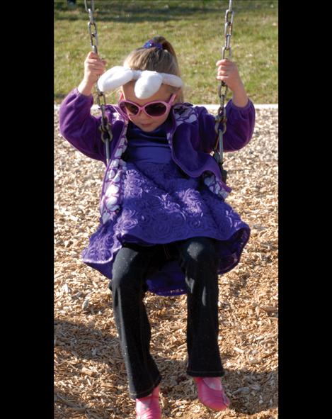 Still wearing her bunny ears, Ziya Walker enjoys some swing time after the Beta Easter Egg Hunt at Boettcher Park.