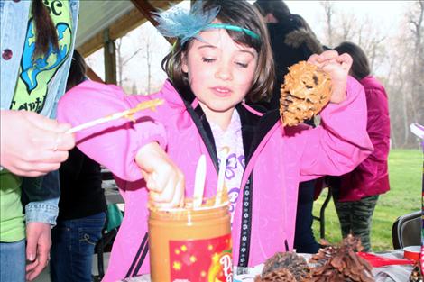Amelia Cronk, 7, spreads peanut butter over a pinecone to make a birdfeeder.