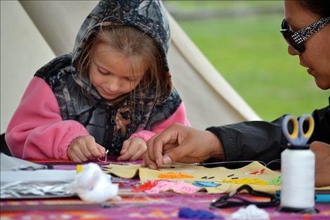 Joselyn Hawbaker, left, tries her hand at beading with help from Corinna Littlewolf.