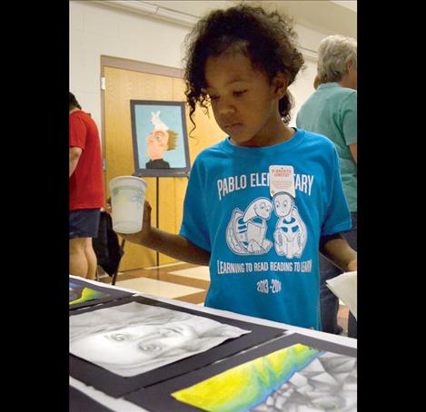 First-grade student Aaliyah Stewart glances at a sketch of a face, a common theme throughout the displays.