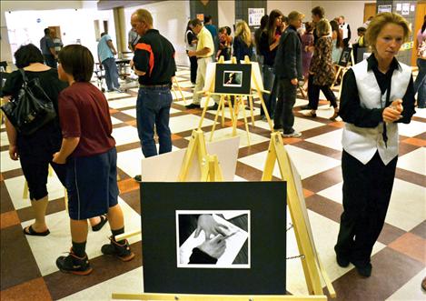 Visitors at the Fine Arts Spring Fling Music Night browse through photographic images created by students.