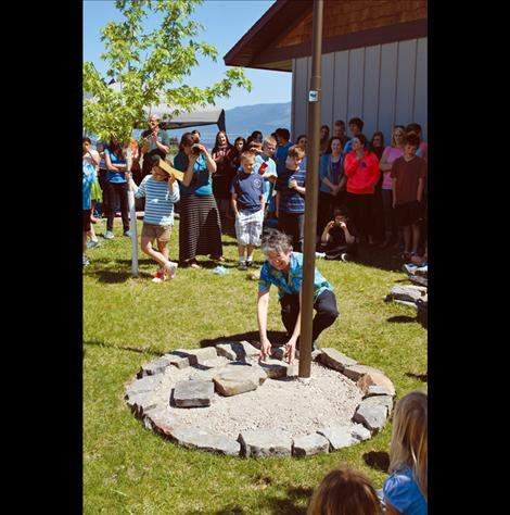 Carolyn Hall places a stone of remembrance beneath the flagpole at Mission Valley Christian Academy. 