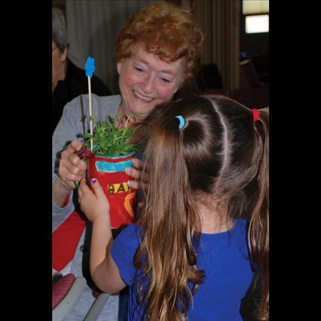 Good Shepherd Lutheran Church Quilter Barb Legoo receives a mug with a potted flower in it  from a Little Lambs preschooler.  