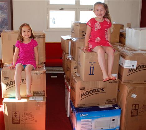 Preschoolers sit on boxes of quilts packed to be shipped as mission quilts. 