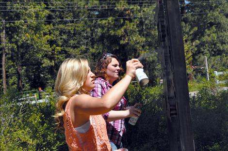 Ronan student Laurel Rigby sprays finish on a sign made by her vo-ag class.  