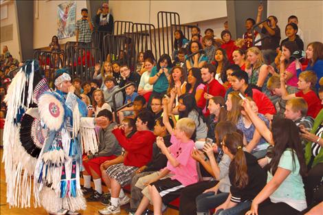 Supaman performs a freestyle rap as people in the audience hold up items to trigger his rhyme.