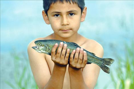 Dillion Irvine shows off a rainbow trout he caught during Fishing Day at Ninepipe.  