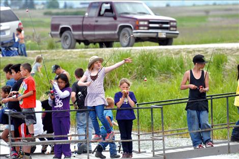 Children fish from a pier at Ninepipe Pond. 