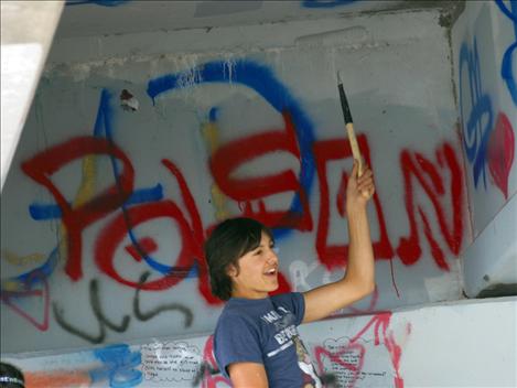 A Polson Middle School student council member, left, paints over graffiti under the Armed Forces Memorial Bridge