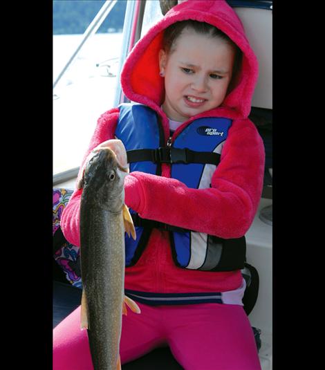 Brandee Reinsberg uses a pair of pliers to hold the lake trout she caught.  