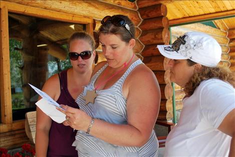 Bobbi Stammers Justine Welker, and Kelly Morigeau observe a scavenger hunt clue found at Ninepipes Lodge on Saturday.