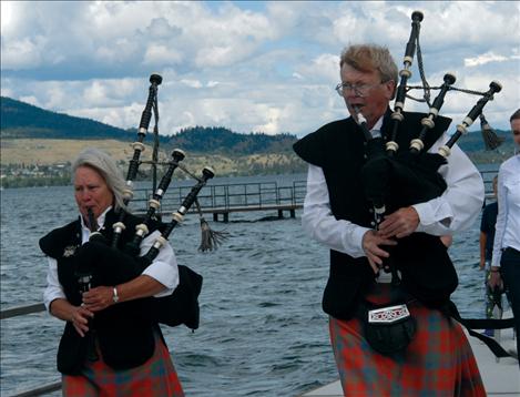 Bagpipers Dick Bratton and Sandy Farrell lead people through the new city dock.
