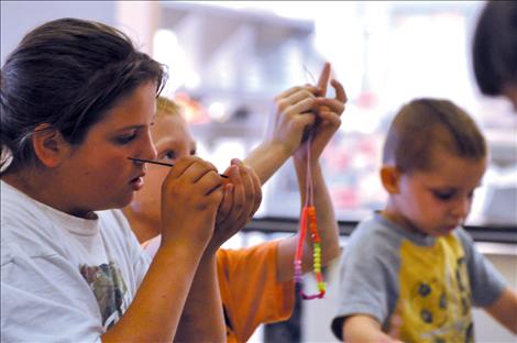 Children make artwork out of macaroni noodles. 