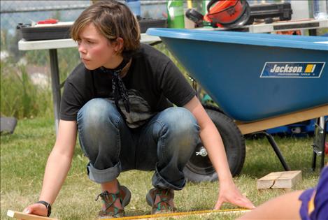 Geneva des-Lyons holds the measuring tape waiting for her partner to mark the cutline.