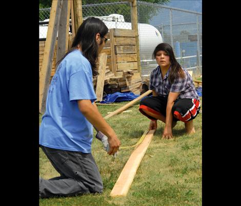 Joseph Salois, left, and Dezirae Kittson measure a board on a sunny afternoon.