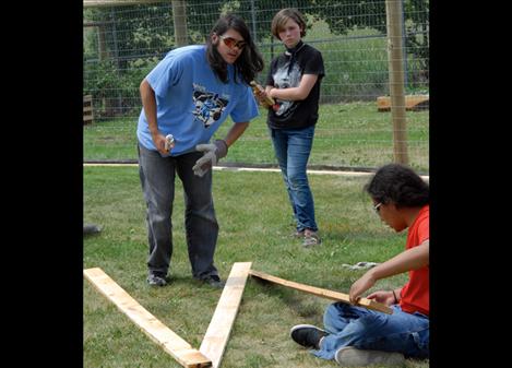 Joseph Salois, left, Geneva des-Lyons and Mars Sandoval mark boards to be used on a fence at the Polson Middle School garden.