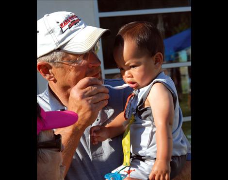 Hu Beaver, left, offers his grandson a bite of huckleberry ice cream at the MVAC’s ice cream social celebrating its first year of operation.