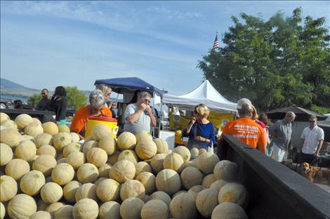 Joey Hettick cuts melons that people taste at the Polson Farmers Market.