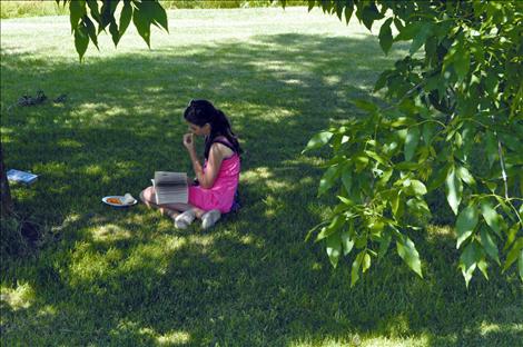 Bella Smith eats and reads in Bockman Park during the finale of Ronan Library’s Summer Reading program