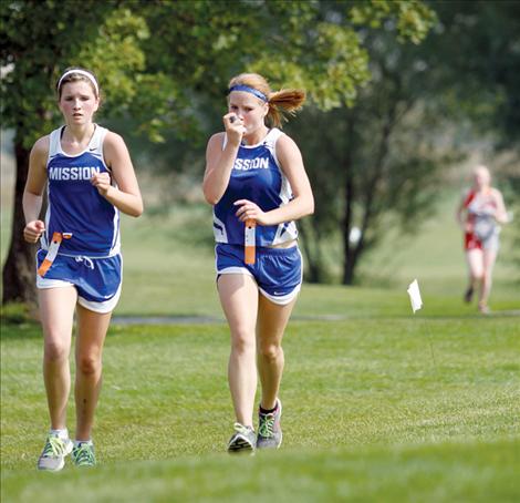 Smoky conditions at the Ronan Invitational prompt Carley Elverud, right, to use an inhaler during the race as she runs alongside teammate Lindsay Johnson.