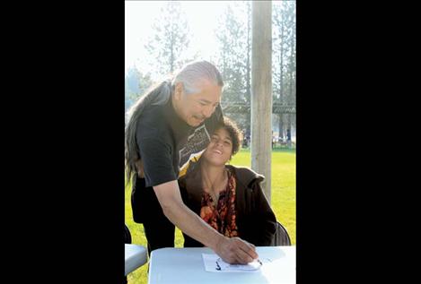 Colleen Brazil hugs Marty Eagle Feathers as he helps her draw a buffalo.