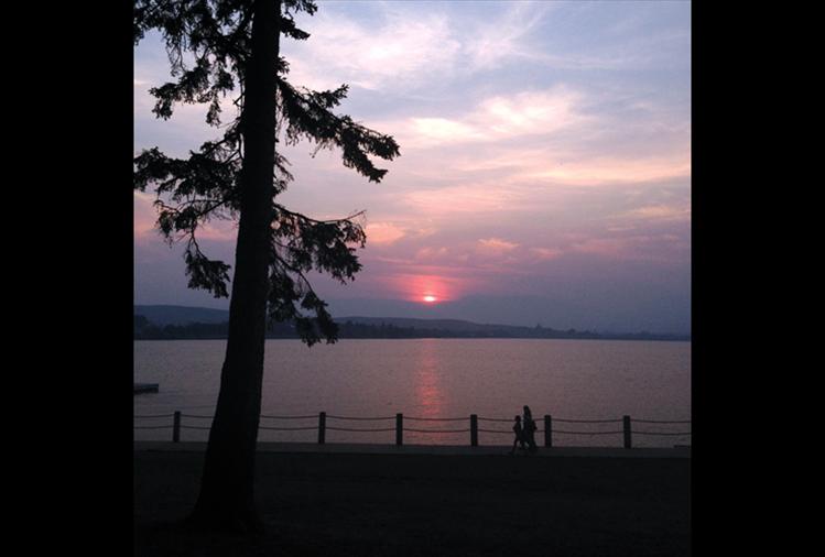 A smoky sunset provided a beautiful backdrop for pedestrians walking along the new  boardwalk in Sacajawea Park in Polson.