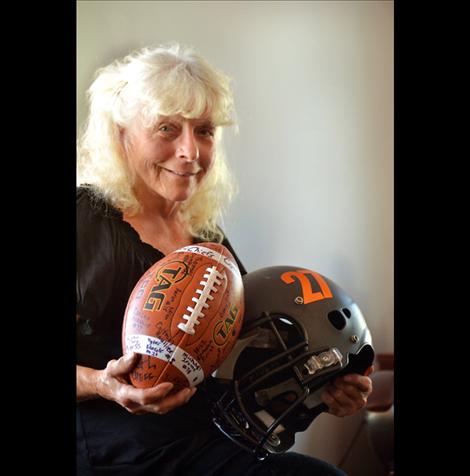 Peschel’s sister, Patty Mikulecky, holds  the football and helmet donated and signed by the 2014 Ronan High School Chiefs  football team.