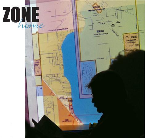 Residents attending the city/county planning board meeting study handouts and a map of Polson zoning districts.