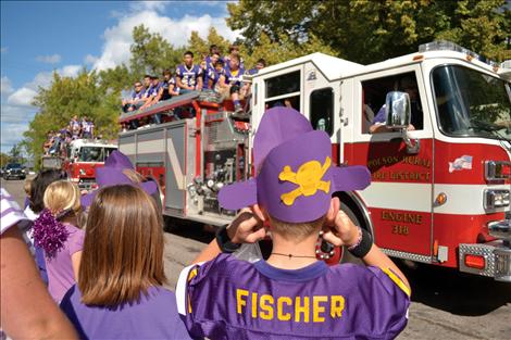 A Linderman Elementary student protects his ears from the siren on the engine carrying the Pirate football team  during Friday’s homecoming parade in downtown Polson.