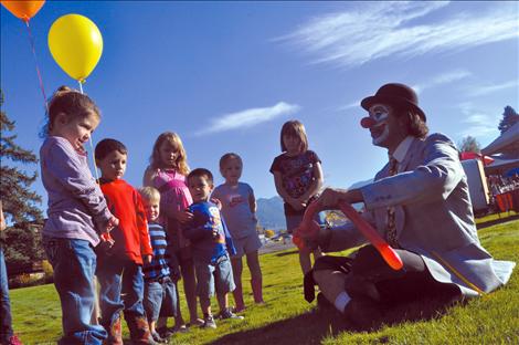 Children watch as a balloon is magically transformed into a dog by a clown at the Ronan Harvest Fest. 