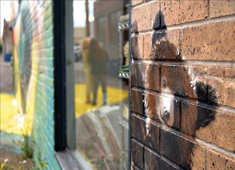 A bear cub peers from the side of the building. The mural includes a racoon, fish, a bison and a bald eagle.