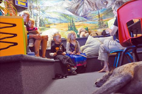 Liam Gingras and Aeryka Hunold enjoy a story read by Andrea Dunn while Library Lion Sadee looks on. 