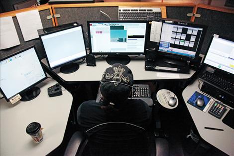 Shelly Wheeler-Burland sits at her dispatch desk surrounded by computer screens. 