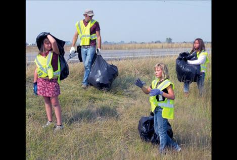 Boys and Girls Club Ronan unit director Lee Schnase walks as a physical barrier between traffic and the barrow pit while young club members pick up trash along U.S. Highway 93 between the scenic turnout and the Charlo turnoff.